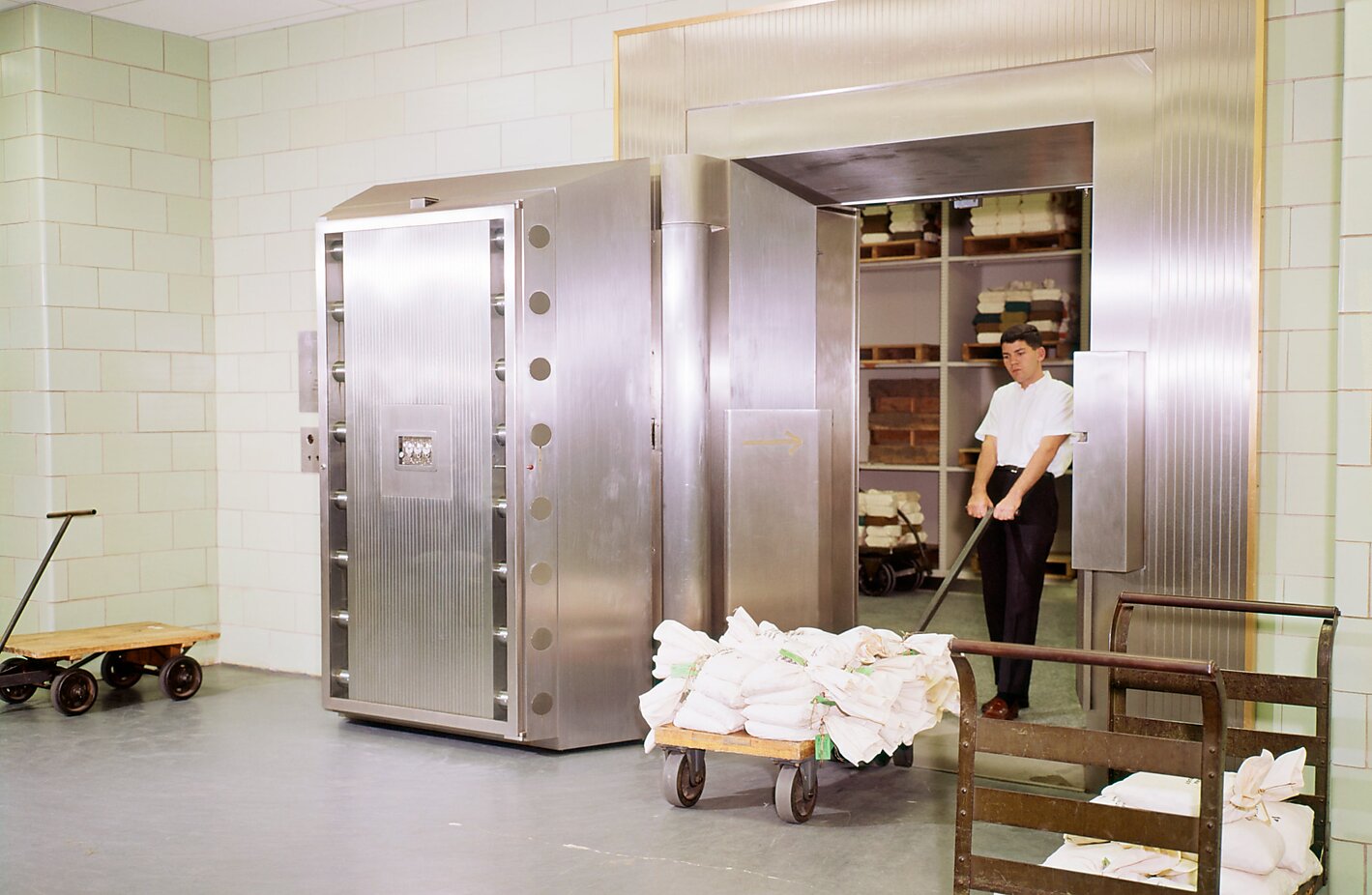 A bank employee wheels bags of cash into a safe.