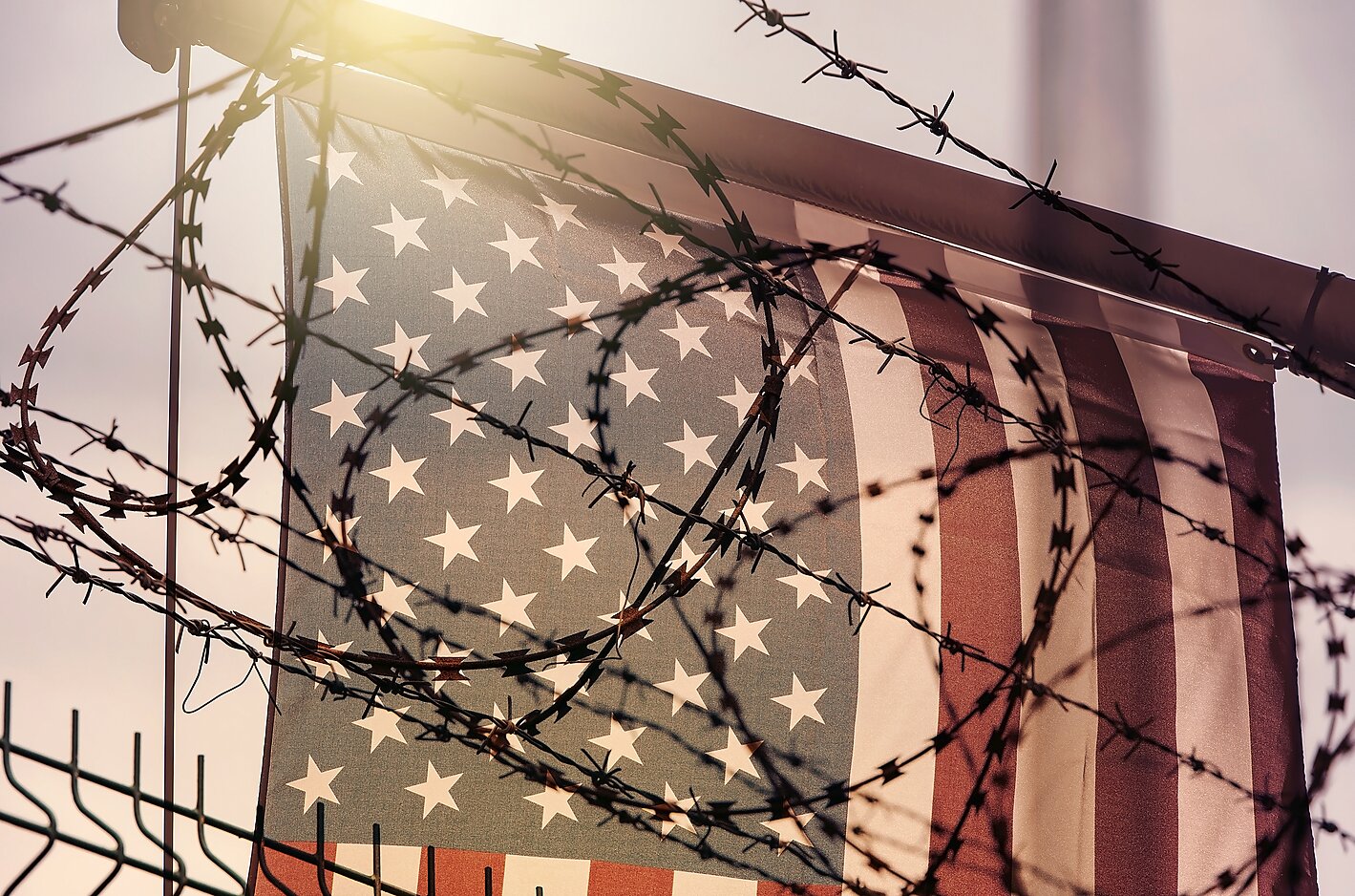 The American flag behind barbed wire at the U.S. border.