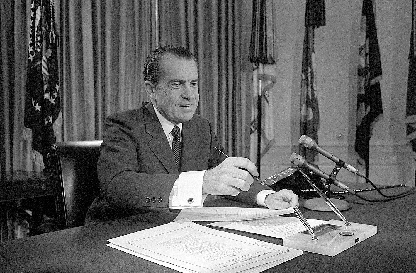 President Richard Nixon sitting at a desk, replacing the pen after re-enacting the vetoing of a 1970 bill for photographers. 