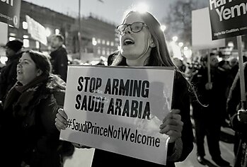 Woman holding stop arming Saudi Arabia sign