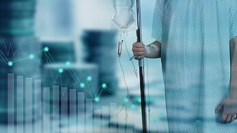 Patient in hospital gown with IV bag and coins in background