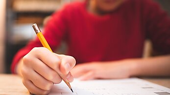 Hands of a child studying at desk 