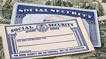 Two Social Security cards with a dollar bill in the background