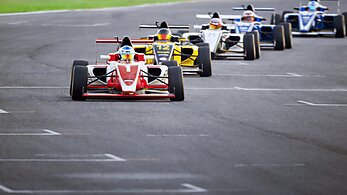 Racing drivers driving open-wheel single-seater racing car cars on racing track.