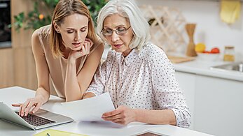 Daughter with mother financial planning at kitchen table