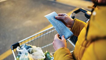 Woman examines her high grocery bill. 