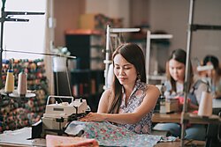 Female blue collar worker working in sewing studio in a row.