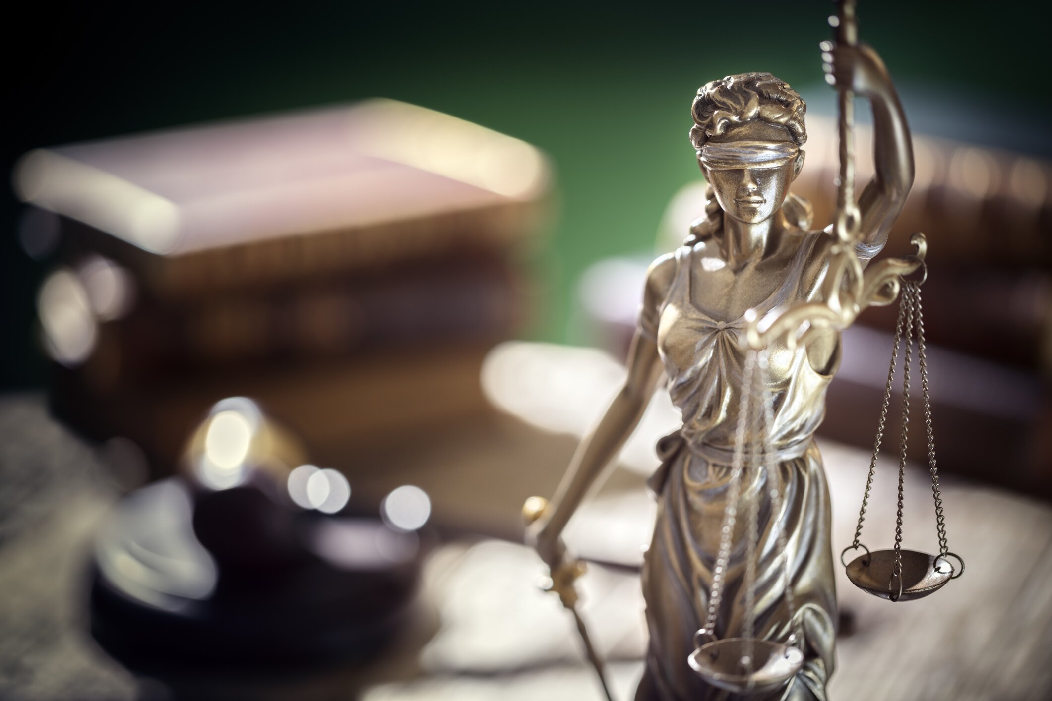Lady justice with a gavel and books on a desk in the background