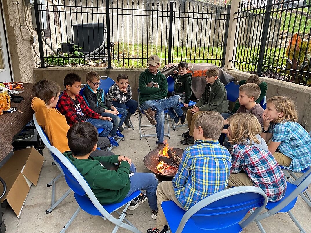Riverside Club students gathered around a fire pit