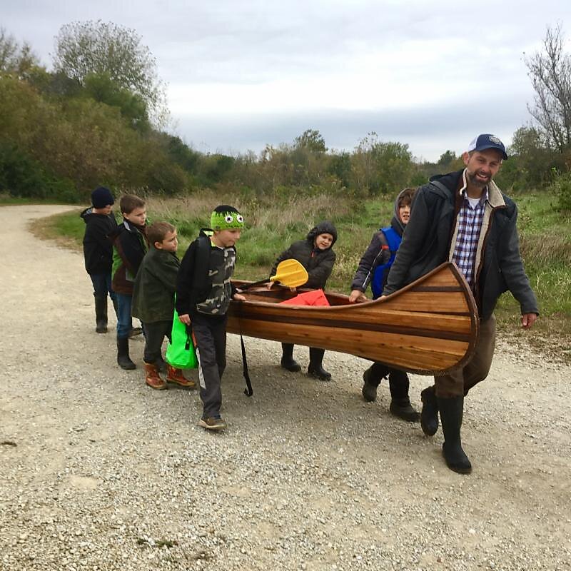 Riverside Club students helping a teacher carry a canoe