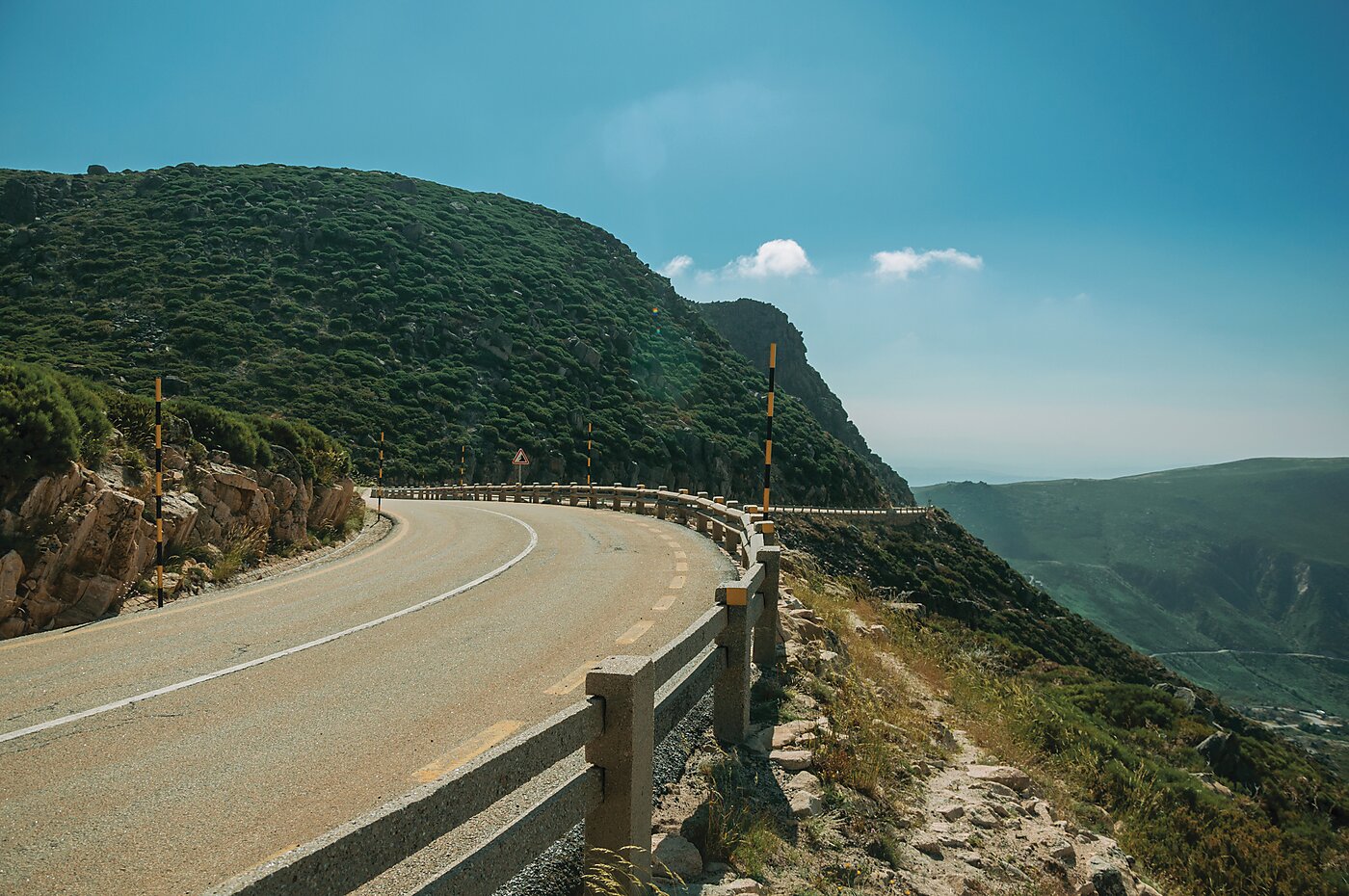 Curved roadway with guardrails passing through mountainous landscape