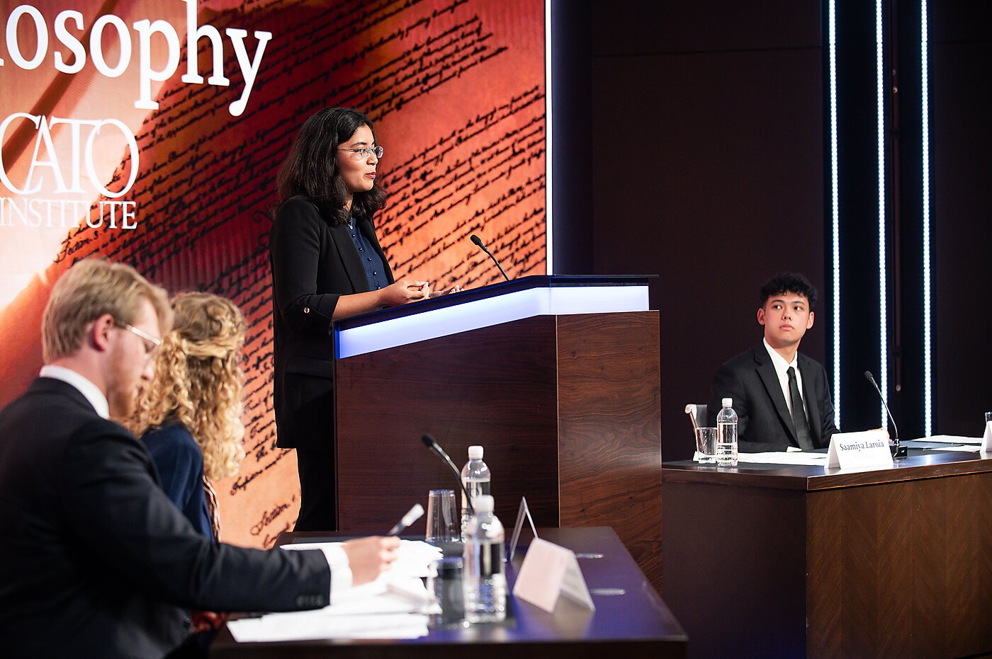 Summer 2025 interns Saamiya Laroia (standing) and Ben Woods (seated, right) participated in the annual Conservatism versus Libertarianism debate with interns from the Heritage Foundation, hosted in 2025 at Cato.